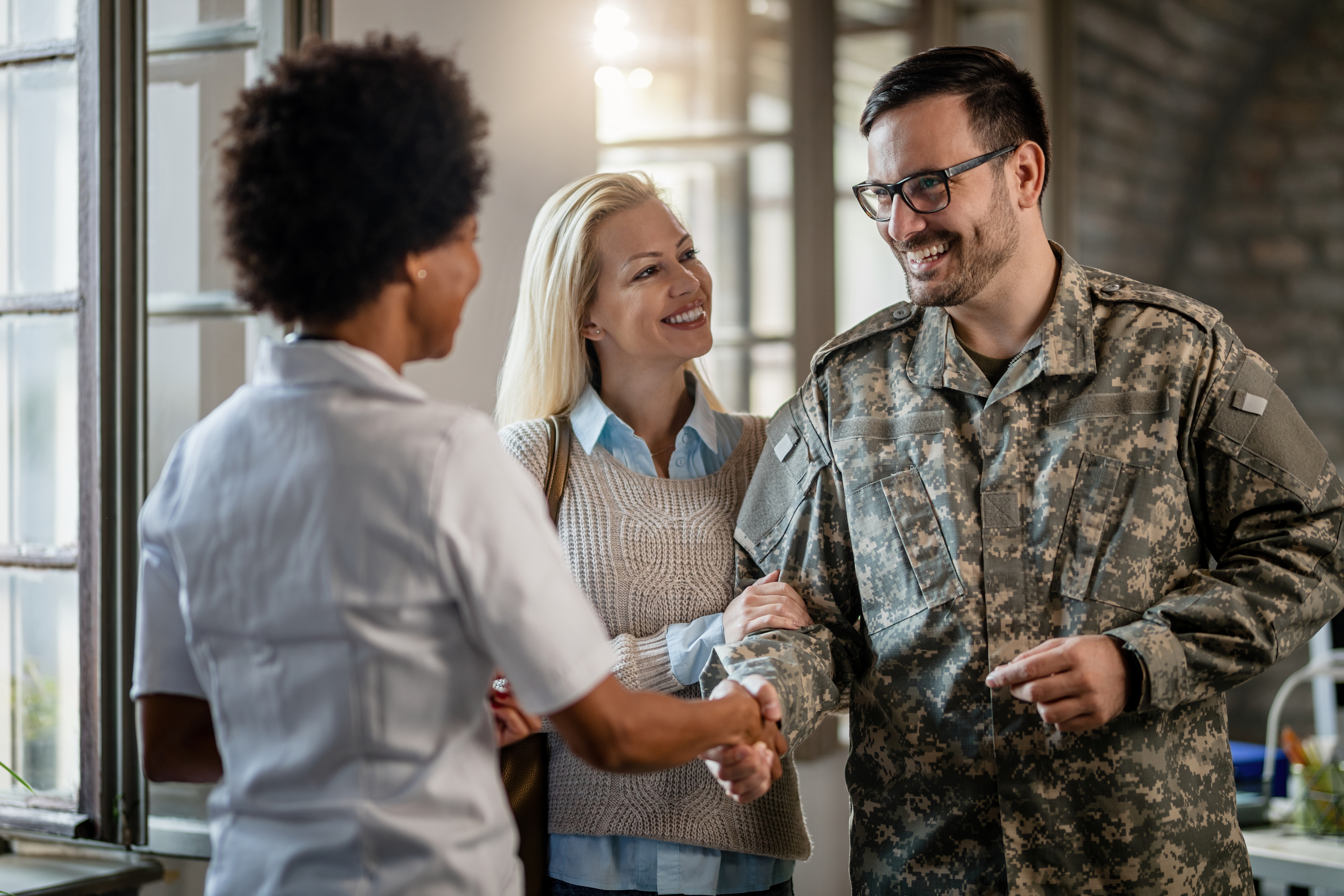 Image of uniformed member with significant other, shaking hands with a third person.